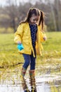 Tranquile child standing in puddle with paper boat in hand and looking at water, preparing to launch ship in fall day. Royalty Free Stock Photo