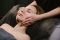 Tranquile woman receiving facial massage in a beauty salon with hands