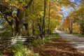 Tranquility scene of a country road in autumn with fence in the foreground