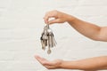 Transfer of house key on a white brick background. Woman's hands with bunch of keys