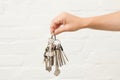 Transfer of house key on a white brick background. Woman's hands with bunch of keys