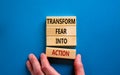 Transform fear into action symbol. Businessman holds wooden blocks with words `Transform fear into action`. Beautiful blue