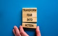 Transform fear into action symbol. Businessman holds wooden blocks with words `Transform fear into action`. Beautiful blue