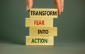 Transform fear into action symbol. Businessman holds wooden blocks with words `Transform fear into action`. Beautiful grey