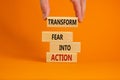 Transform fear into action symbol. Businessman holds wooden blocks with words `Transform fear into action`. Beautiful orange