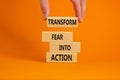 Transform fear into action symbol. Businessman holds wooden blocks with words `Transform fear into action`. Beautiful orange