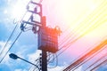 Transformer High voltage electricity pole and power line with blue cloudy sky background.