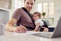 Transgender Father Working From Home On Laptop Looking After Baby Son In Sling Royalty Free Stock Photo