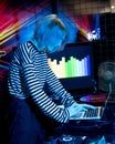 Transgender girl - DJ, mixes the soundtrack on laptop, in front of her there is a mixing console