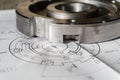 The transition flange after processing lies on the technical drawing. Detail ready to work with a drawing together in mechanical Royalty Free Stock Photo