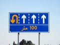 Translation of the Arabic (100 M one hundred meters) at a side informative traffic sign board showing 4 lanes