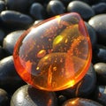 Translucent amber stone with embedded bubbles sits atop smooth Royalty Free Stock Photo
