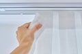 Translucent white textured curtain on window, close-up of cornice and fabric gathered on braid