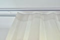 Translucent white textured curtain on window, close-up of cornice and fabric gathered on braid