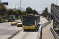 A Transmilenio yellow bus with two taxis transiting over \