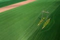 Transmission tower supporting overhead power line through cultivated crops field, aerial view Royalty Free Stock Photo