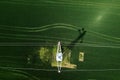 Transmission tower supporting overhead power line through cultivated crops field, aerial view from drone pov Royalty Free Stock Photo