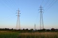 Transmission towers carrying high voltage electric power lines. Electricity pylons in the field Royalty Free Stock Photo