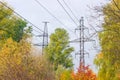 Transmission towers of overhead power lines against autumn foliage