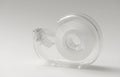 Transparent adhesive tape dispenser with clear tape roll on a light neutral background Royalty Free Stock Photo