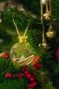 Transparent ball with a key and a letter in the golden sand, hanging on a Christmas tree.
