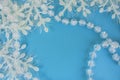 Transparent beads to decorate the Christmas tree and white snowflakes with tinsel on a blue background Royalty Free Stock Photo