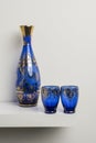 A transparent blue glass bottle with gold decorations and glasses of the same set Royalty Free Stock Photo