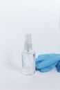A transparent bottle with an antiseptic stands on a light background, next to medical gloves, vertical photo Royalty Free Stock Photo