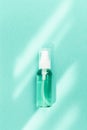 Transparent bottle with cosmetic product, soap or shampoo on mint colored background. Bright daylight