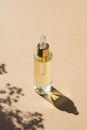 Transparent bottle with dropper pipette with serum or essential oil with beautiful flowers shadows. Royalty Free Stock Photo