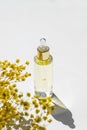 Transparent bottle with dropper pipette with serum or essential oil with beautiful yellow flowers. Royalty Free Stock Photo