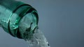 Transparent bottle pouring wine closeup. Bubbling white alcohol flowing down.