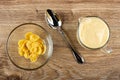 Transparent bowl with corn flakes, spoon, pitcher with yogurt on wooden table. Top view Royalty Free Stock Photo