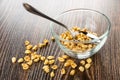 Transparent bowl with puffed wheat, spoon, scattered puffed wheat on table