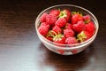 Transparent bowl with strawberries and raspberries on a brown wooden background Royalty Free Stock Photo
