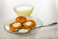 Bowl with condensed milk, soft waffles poured condensed milk, spoon in saucer on wooden table Royalty Free Stock Photo