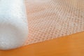 Transparent bubble wrap roll for packaging fragile items on brown wooden table Royalty Free Stock Photo