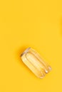 Transparent can of water on yellow background. Monochrome image. New package of clear water in plastic bottle as can