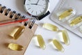 Transparent capsules with fish oil, notepad, blister, fountain pen and watch lie on a white background. Taking medications on a