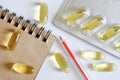 Transparent capsules with fish oil, notepad, blister, fountain pen and watch lie on a white background. Taking medications on a