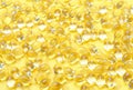 Transparent capsules of vitamin D on a yellow background close-up, texture and background.