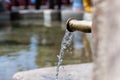 Transparent clean water flows in stream from copper tap on background in bright sunlight Royalty Free Stock Photo