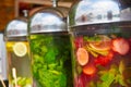 Transparent containers with natural lemonades made from mint, lemon, strawberry and lime on the street counter.