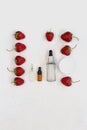 Transparent cosmetic serum in bottle with pipette next to red fresh strawberry