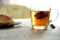 Transparent cup with brewed tea bag is on the table next to the plate