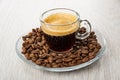 Transparent cup with coffee espresso in saucer with coffee beans on table Royalty Free Stock Photo