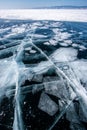 Transparent dark ice on Lake Baikal with frozen pieces of ice and large beautiful cracks.