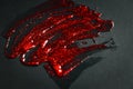 Transparent gel with red glitters smeared on black paper Royalty Free Stock Photo