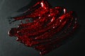 Transparent gel with red glitters smeared on black paper Royalty Free Stock Photo