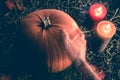 A transparent ghost hand reaching out to touch a big orange pumpkin on dark rustic wood background with hey and candles Royalty Free Stock Photo